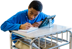 An adolecent boy doing school work at his desk.
